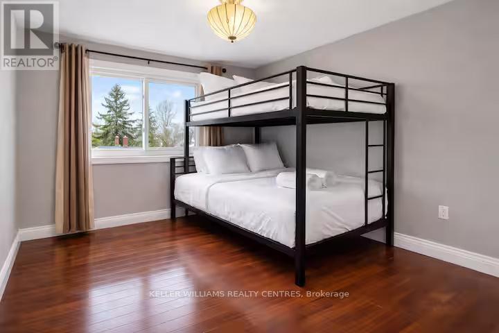 A bedroom with a bunk bed and a window overlooking a tree.