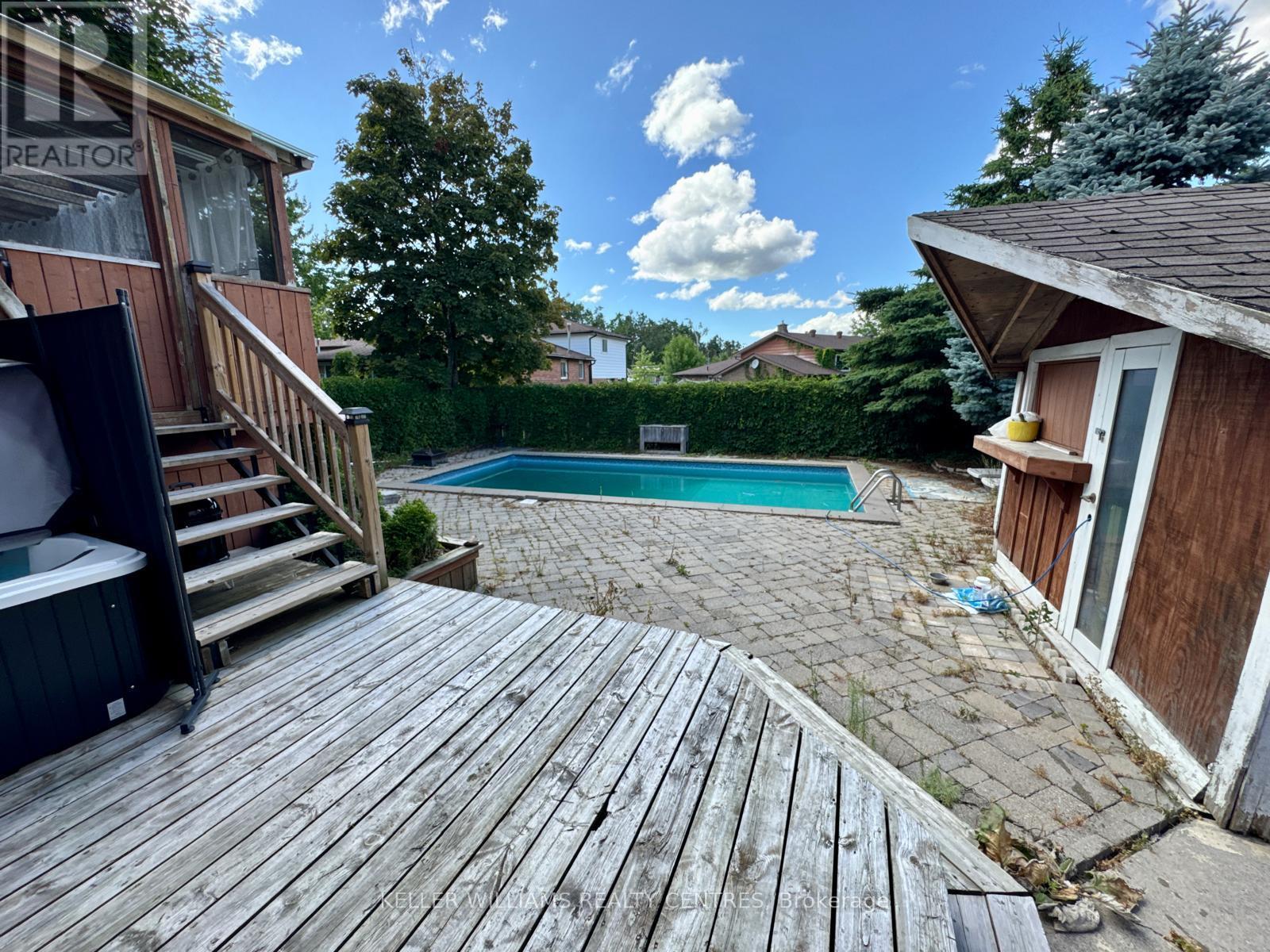 A wooden deck leads to a small pool in a backyard.