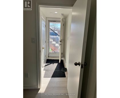 A hallway with a black mat on the floor leading to a door.