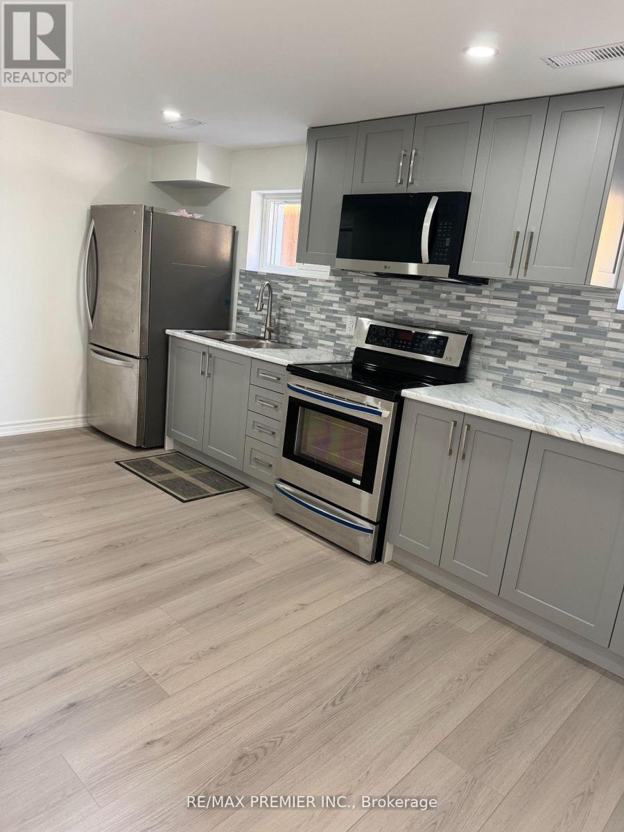 A kitchen with a refrigerator, microwave, oven, and sink.