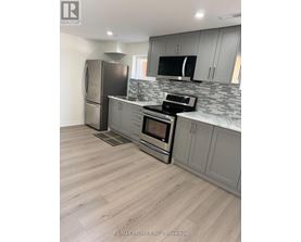 A kitchen with a refrigerator, microwave, oven, and sink.