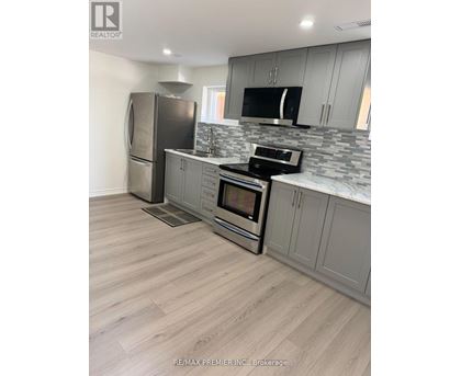 A kitchen with a refrigerator, microwave, oven, and sink.