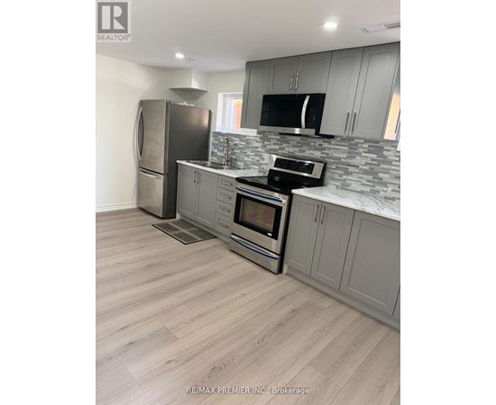 A kitchen with a refrigerator, microwave, oven, and sink.