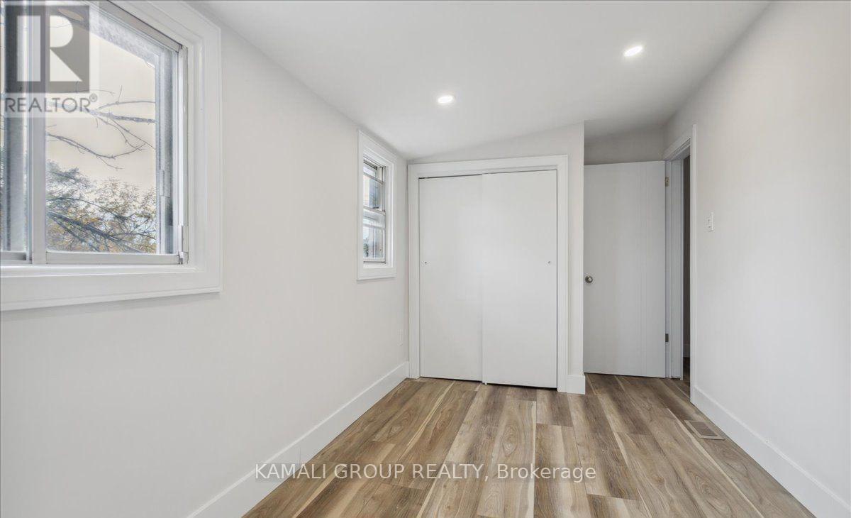 A room with a white door and a window with a view of trees outside.