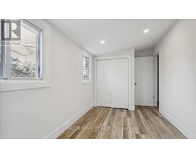 A room with a white door and a window with a view of trees outside.
