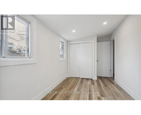 A room with a white door and a window with a view of trees outside.