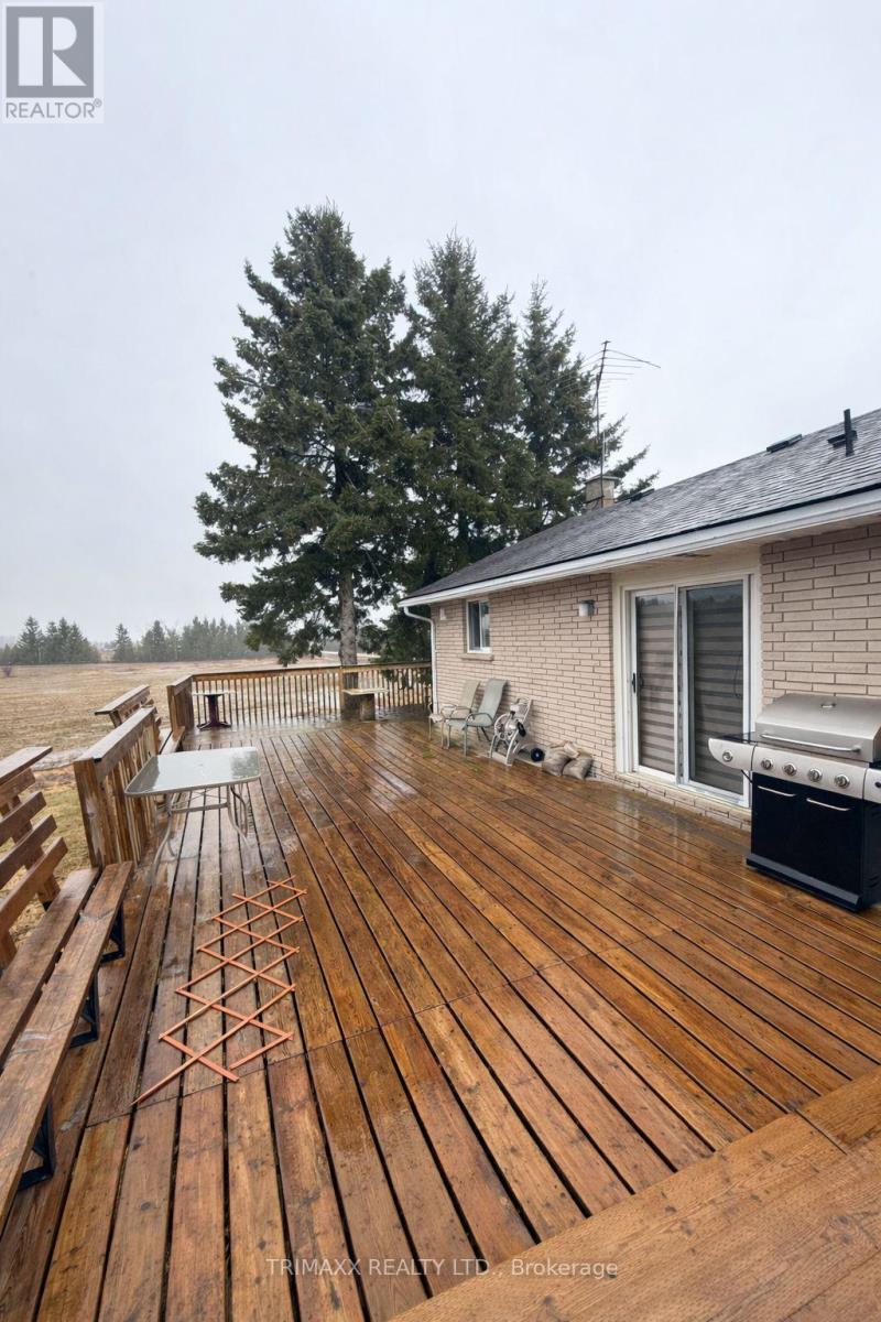 A wooden deck with a bench and a grill on a cloudy day.