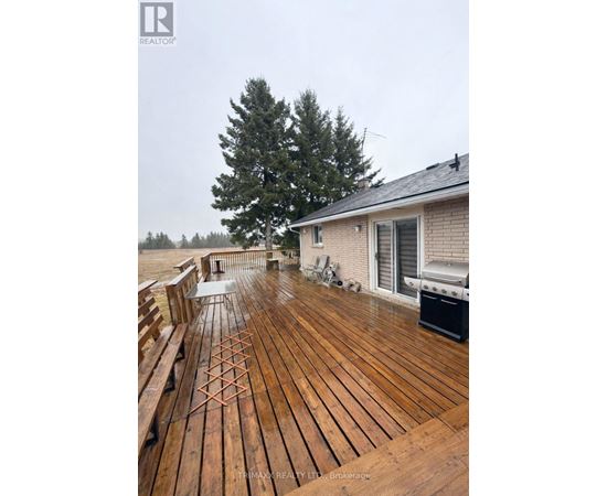 A wooden deck with a bench and a grill on a cloudy day.