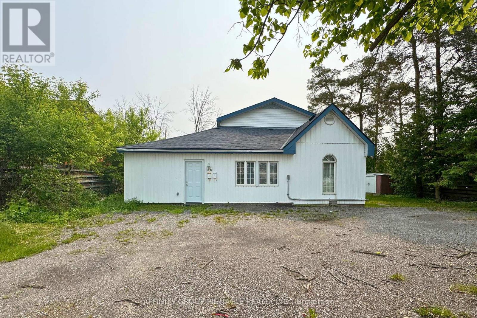 A white house with a blue roof and a gravel driveway in front.