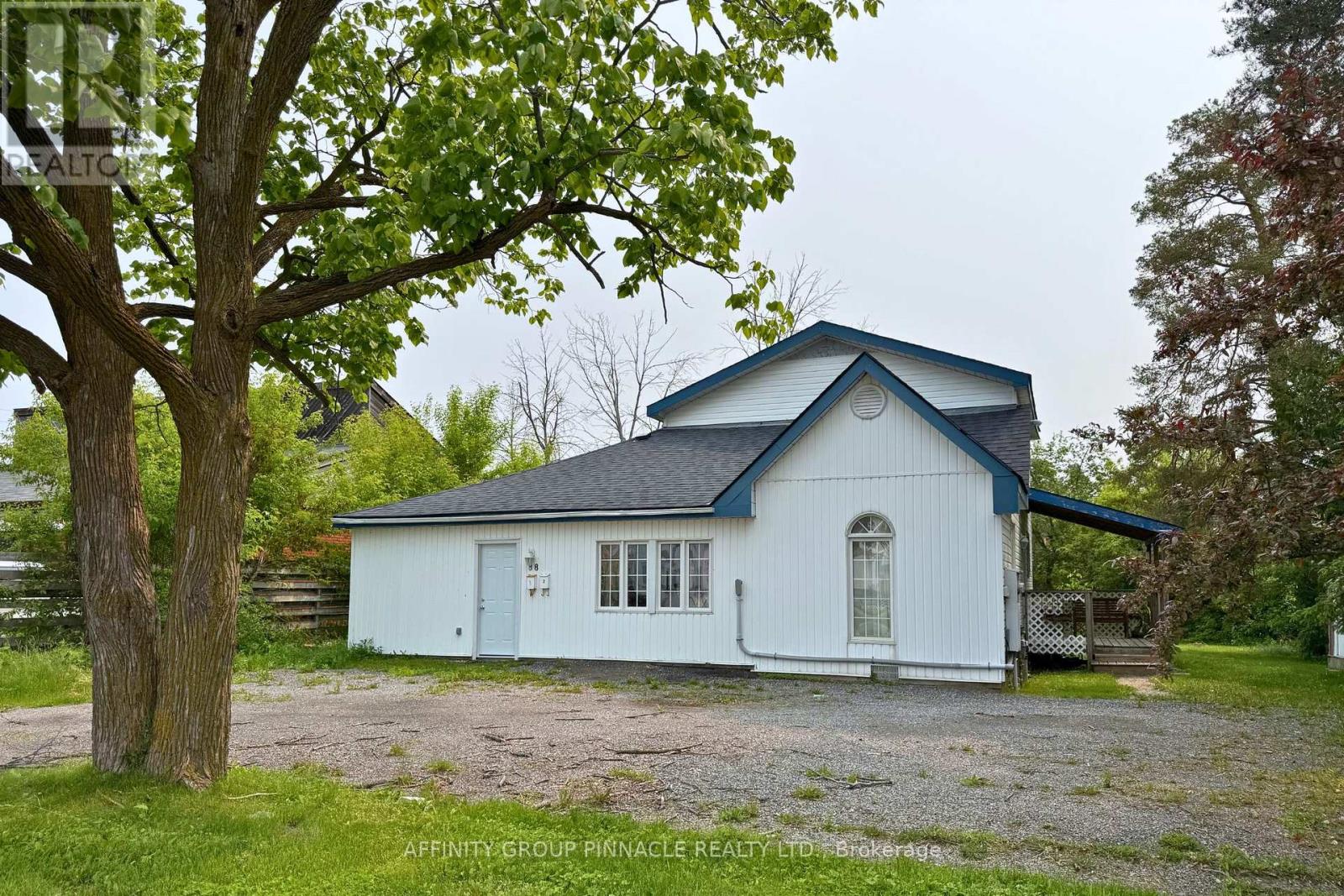 A white house with a blue roof is surrounded by greenery.