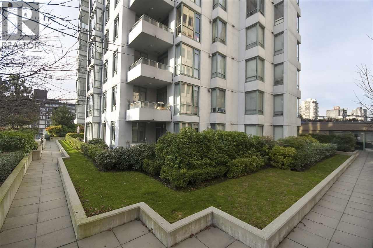 A modern apartment building with a well-maintained lawn in front.