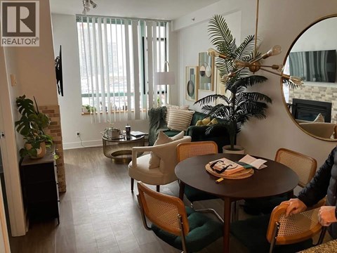 A living room with a table and chairs and a person sitting on a chair.