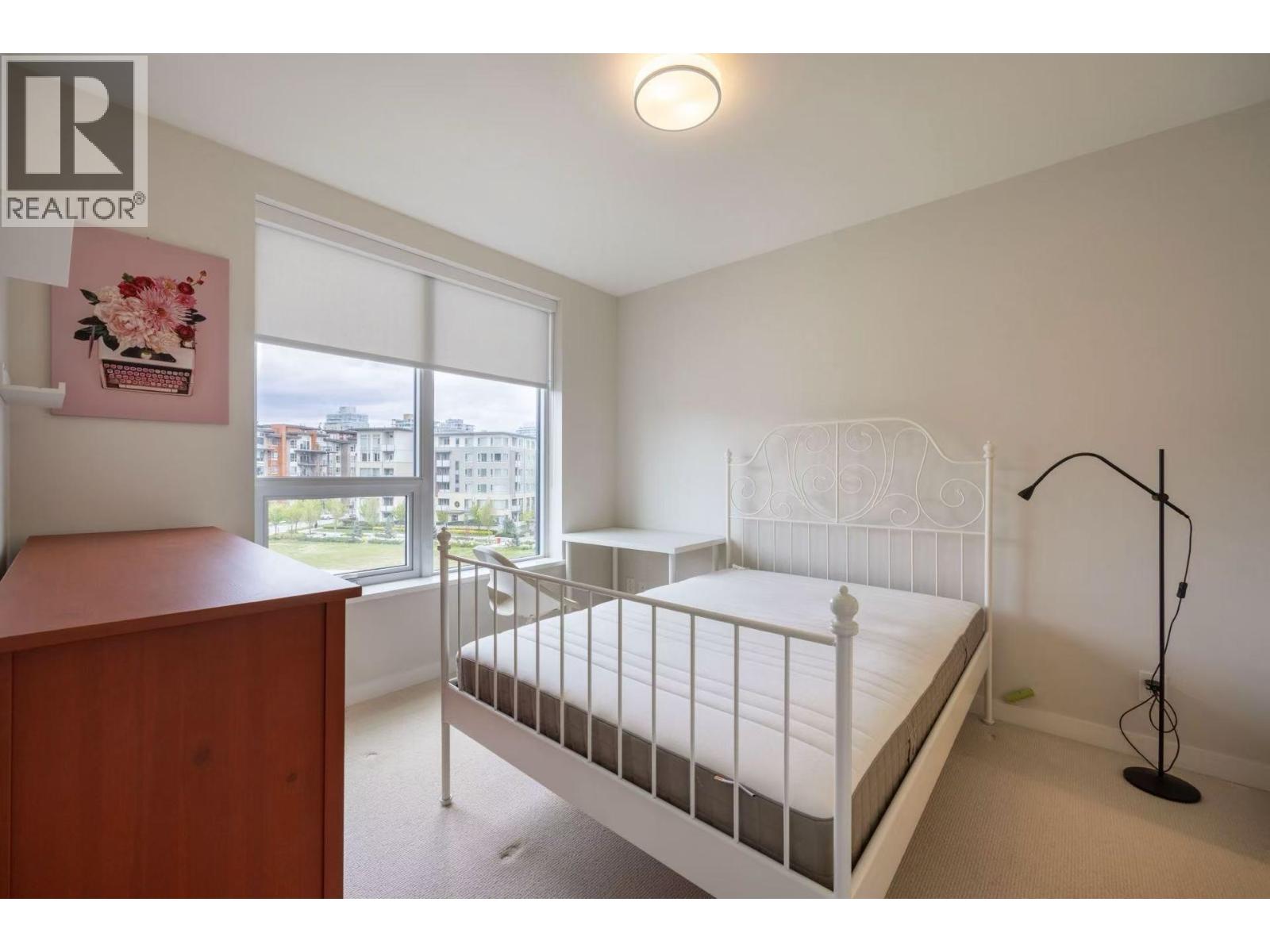 A bedroom with a white bed and a wooden dresser.