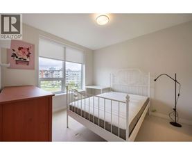 A bedroom with a white bed and a wooden dresser.
