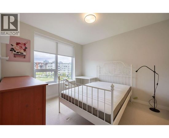 A bedroom with a white bed and a wooden dresser.