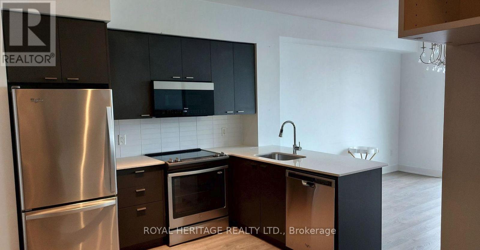 A kitchen with a stainless steel refrigerator and black cabinets.