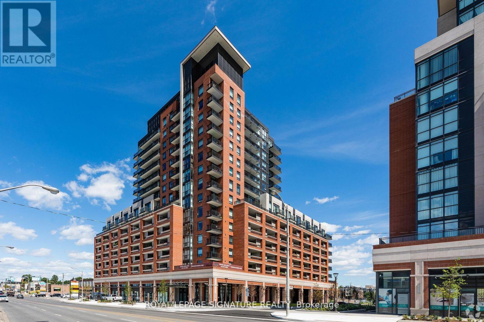 A tall building with a glass facade is situated next to a shorter building with a brick facade.