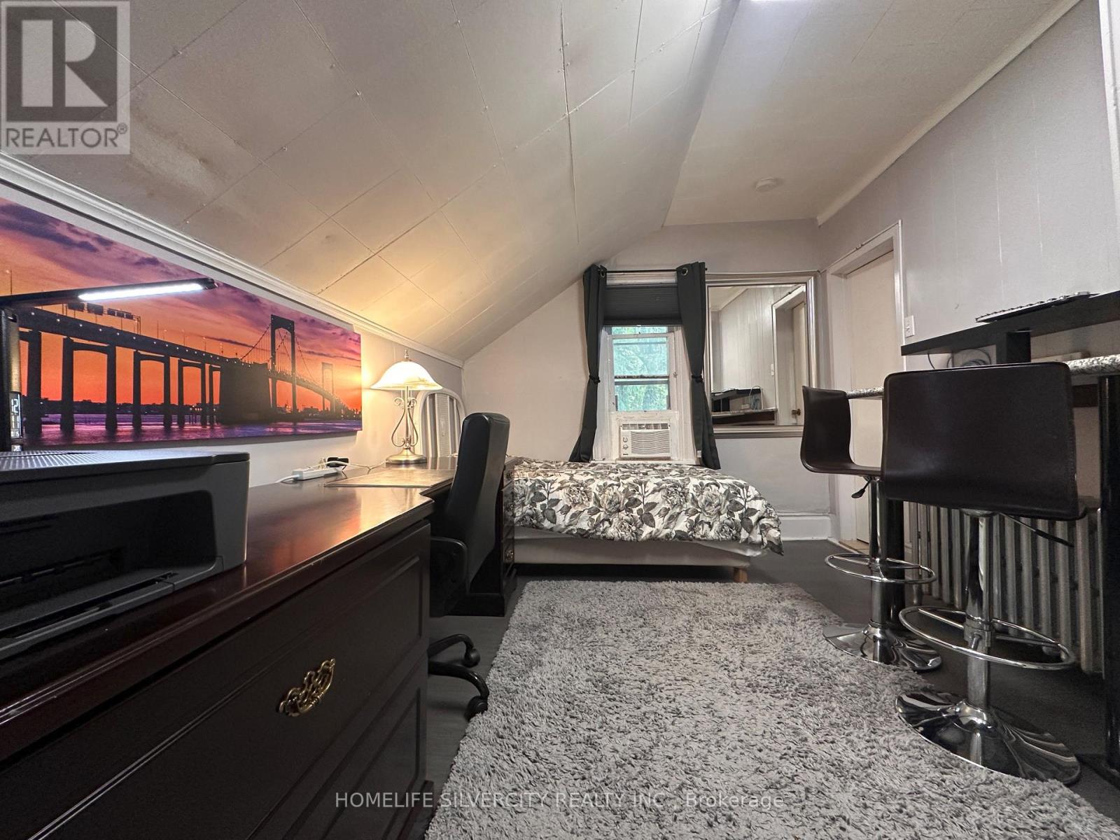 A bedroom with a bed, chair, and a poster on the wall.
