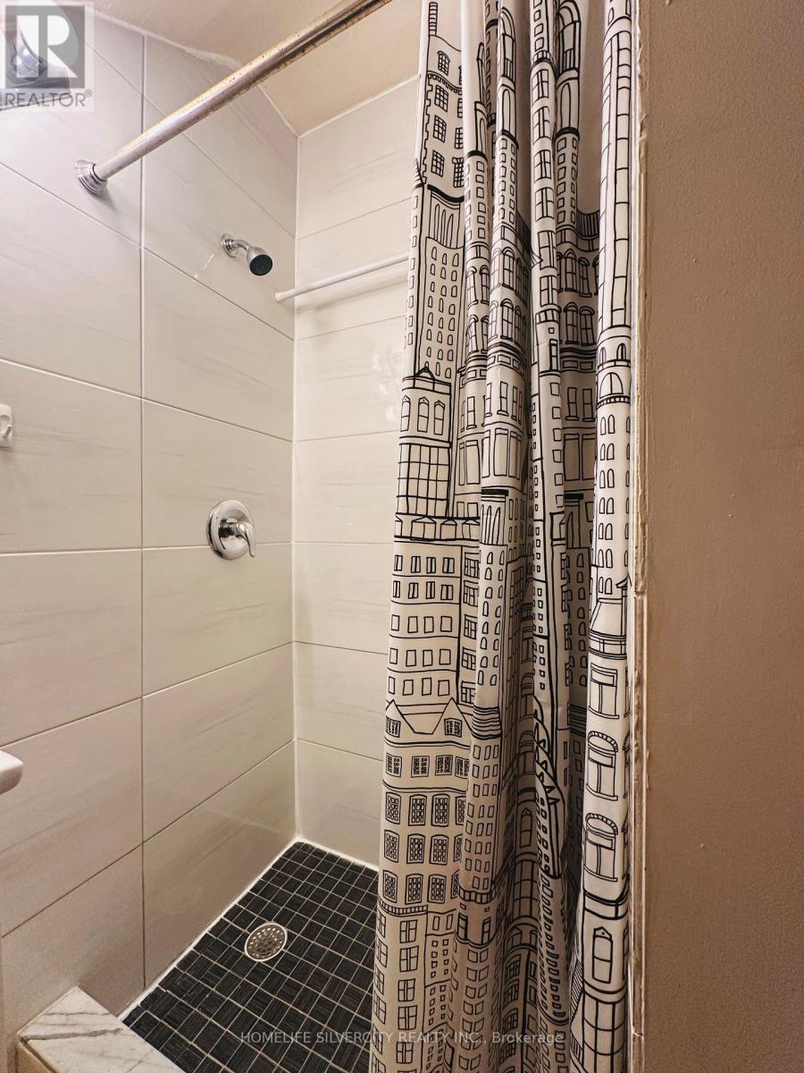 A shower curtain with a building pattern hangs in a bathroom.