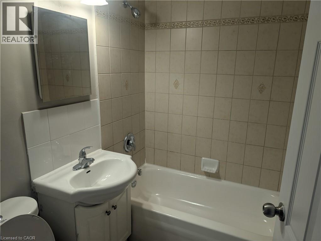 A white sink and bathtub in a bathroom with a mirror above the sink.