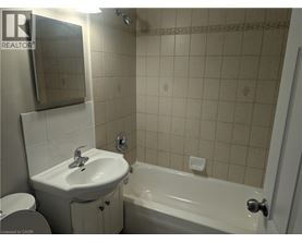 A white sink and bathtub in a bathroom with a mirror above the sink.