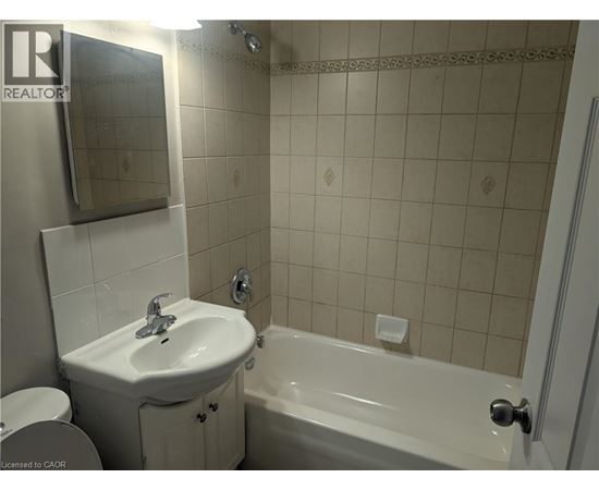 A white sink and bathtub in a bathroom with a mirror above the sink.