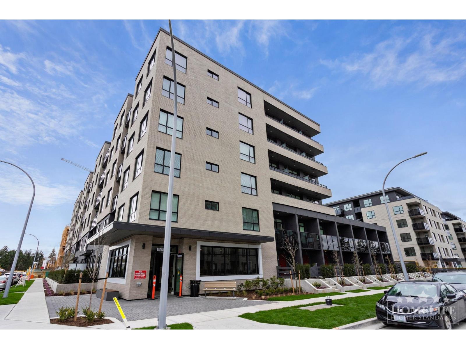 A modern apartment building with a parking lot in front.