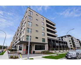 A modern apartment building with a parking lot in front.