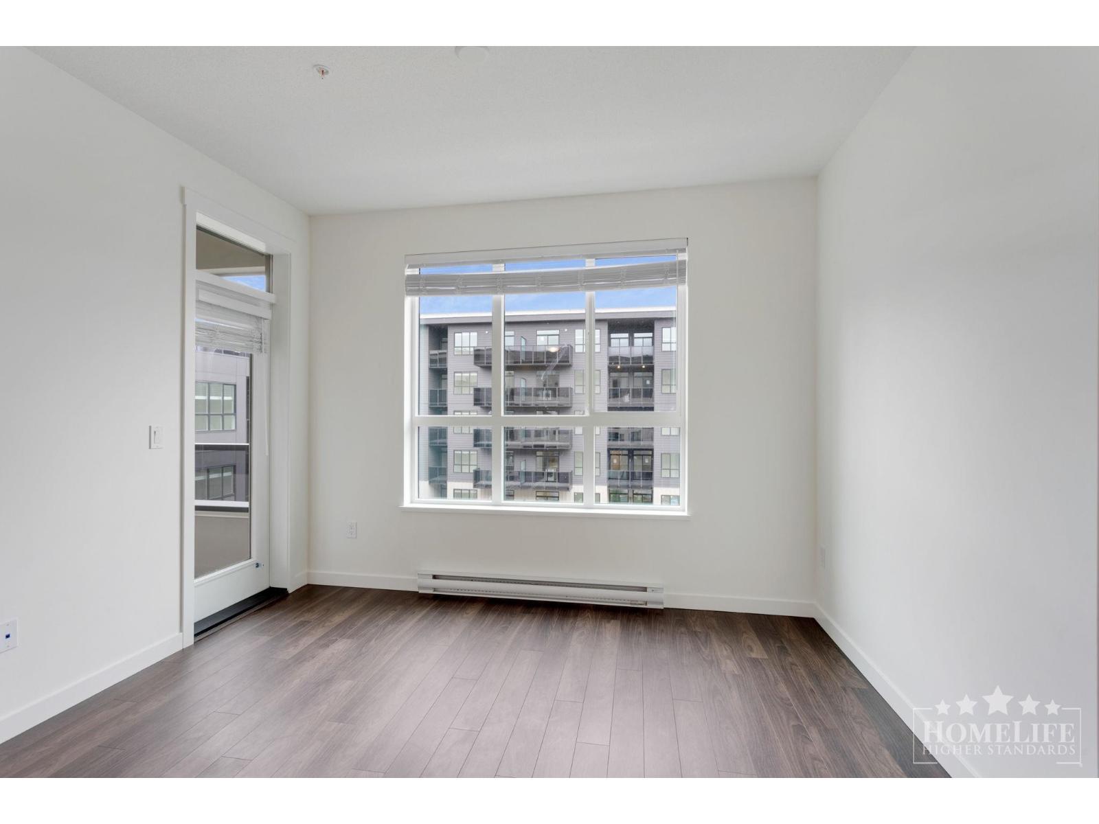 A large empty room with a window and wooden floors.