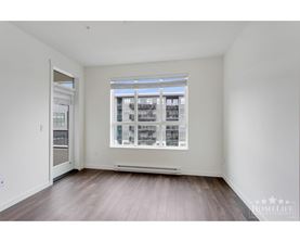 A large empty room with a window and wooden floors.