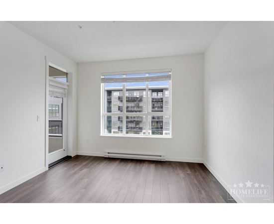 A large empty room with a window and wooden floors.