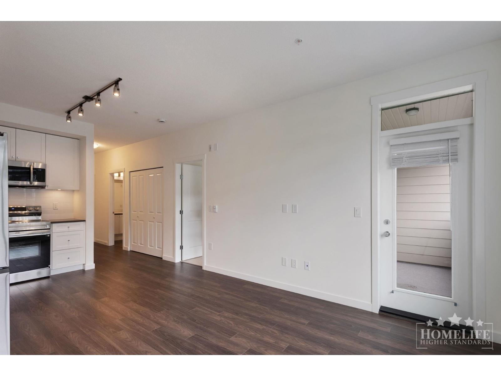 A spacious kitchen with white cabinets and a wooden floor.