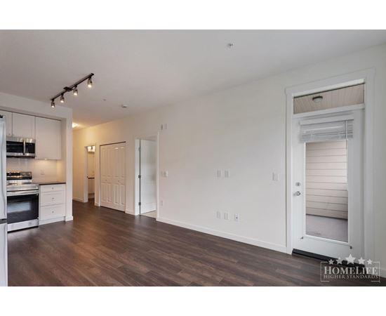 A spacious kitchen with white cabinets and a wooden floor.
