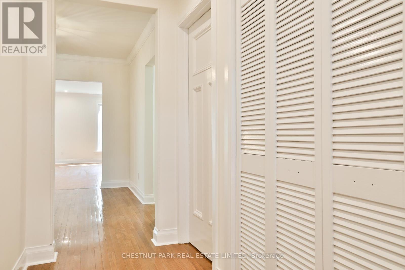 A hallway with white walls and wood floors.