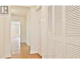 A hallway with white walls and wood floors.