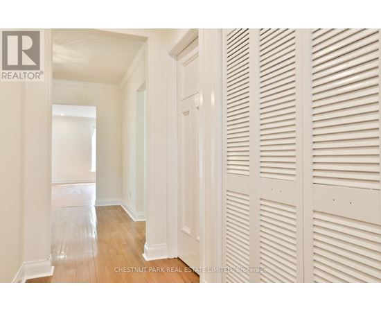 A hallway with white walls and wood floors.