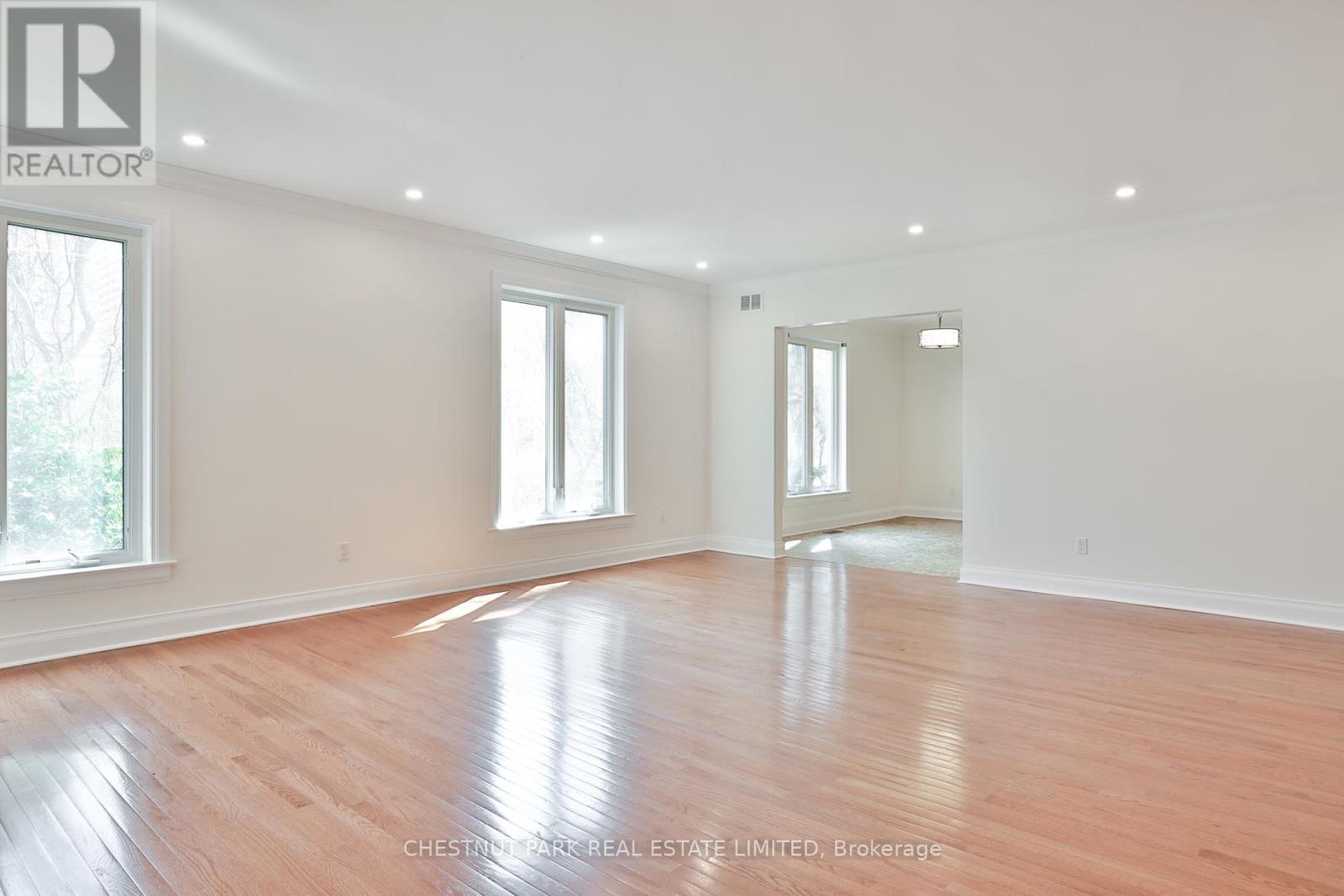 A spacious room with wooden flooring and white walls.