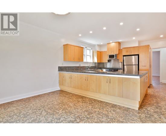 A large kitchen with wooden cabinets and a patterned floor.
