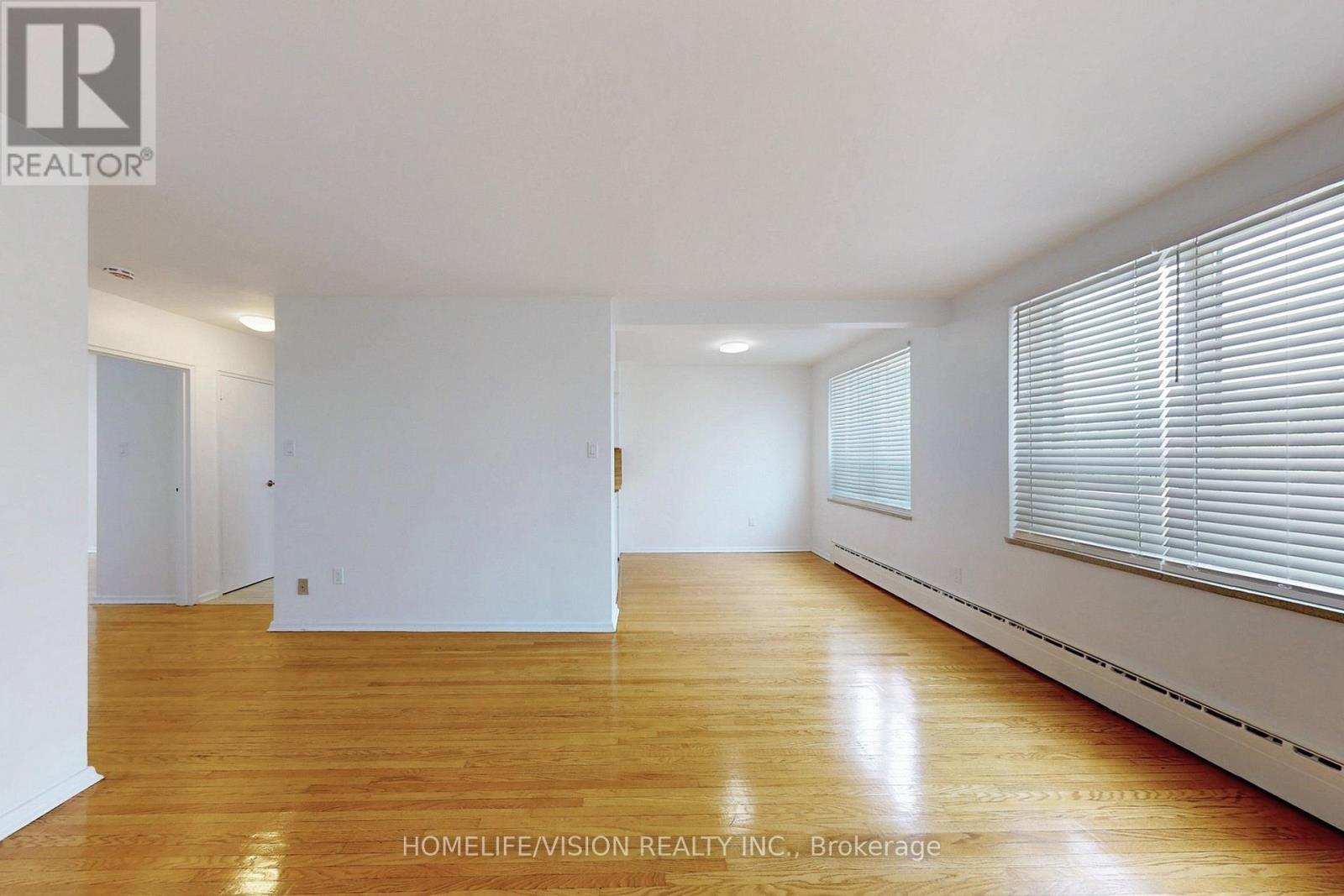 A spacious room with wooden flooring and white walls.