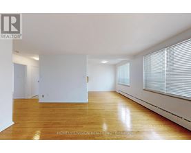 A spacious room with wooden flooring and white walls.