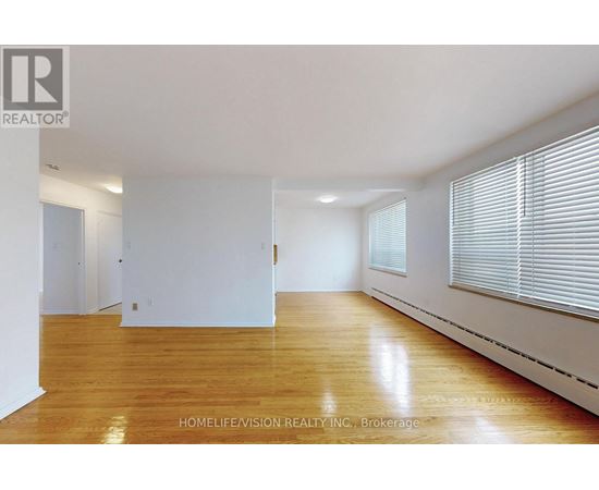 A spacious room with wooden flooring and white walls.