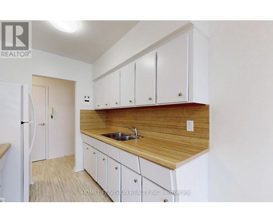 A kitchen with white cabinets and a wooden countertop.