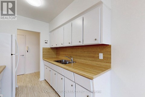 A kitchen with white cabinets and a wooden countertop.