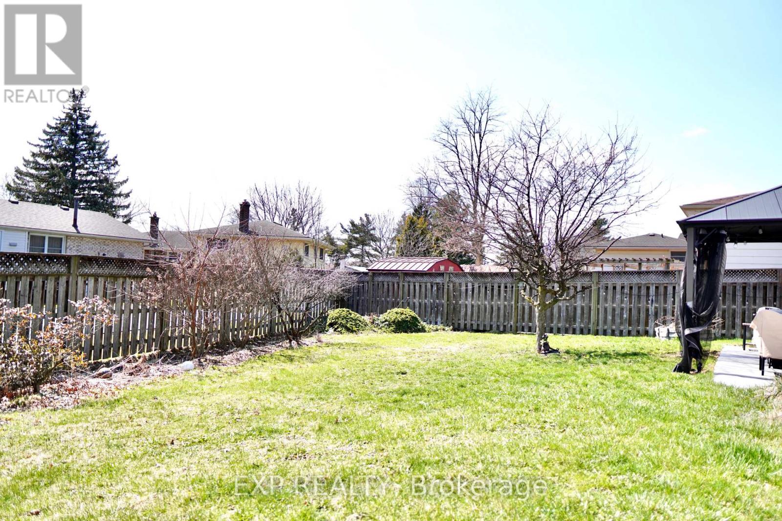 A backyard with a fence, a tree, and a shed.