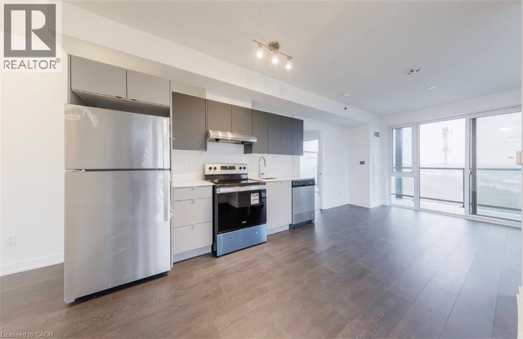 A modern kitchen with a stainless steel refrigerator and wooden flooring.