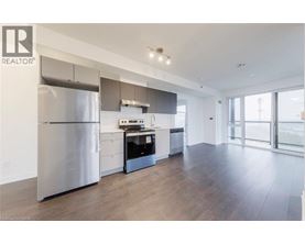 A modern kitchen with a stainless steel refrigerator and wooden flooring.