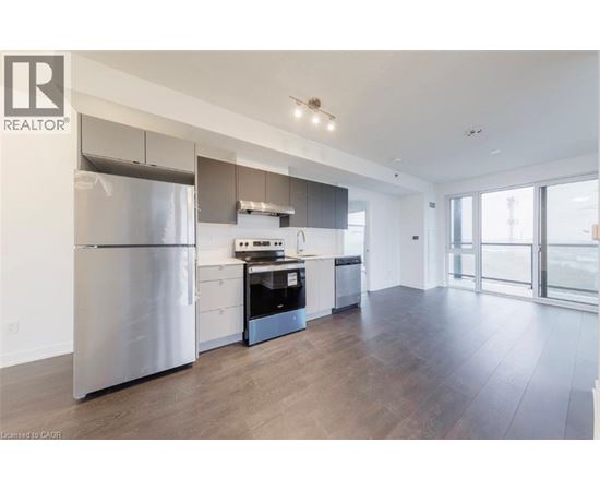A modern kitchen with a stainless steel refrigerator and wooden flooring.