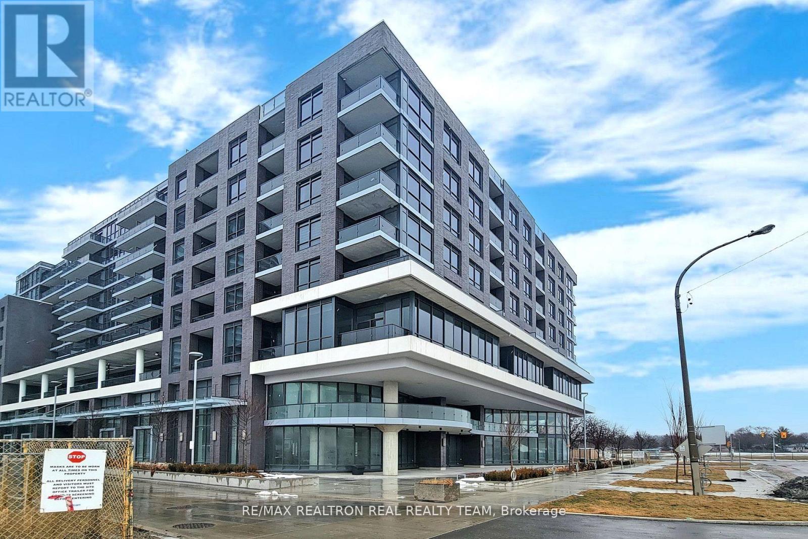 A large, modern building with a glass entrance and a sign that reads RE/MAX REALTRON REALTY TEAM, Brokerage.