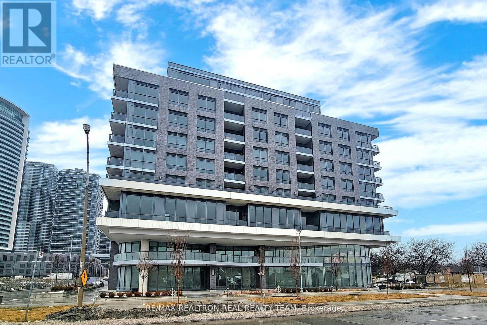 A modern multi-story building with a glass facade and a large entrance.