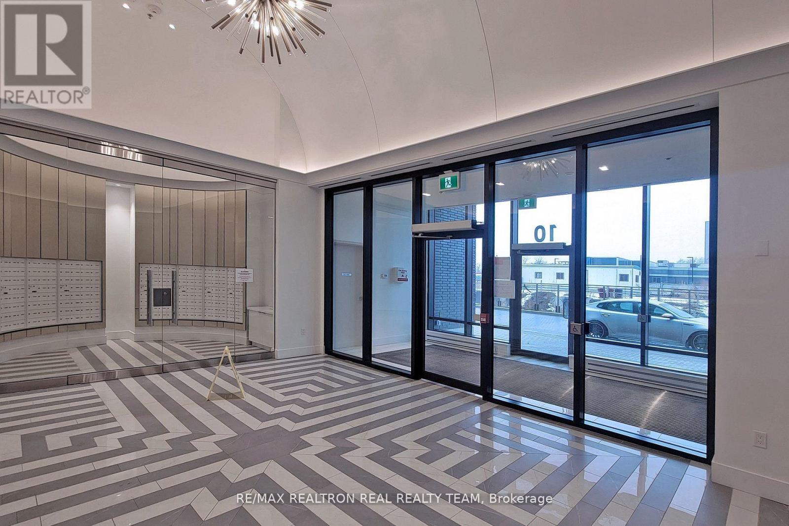 A hallway with a large glass door and a chandelier hanging from the ceiling.